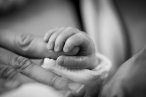 un bebé cogiendo con fuerza la mano de su madre